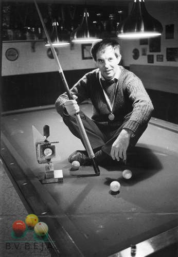 Wereldkampioen artistiek in 1985, Jean Bessems op de plek waar hij thuishoort, de biljarttafel, met de trofee die hij als wereldkampioen kunststoten won.